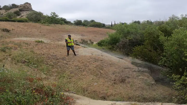man in yellow safety vest spraying fire retardant on bushes by Urbntek